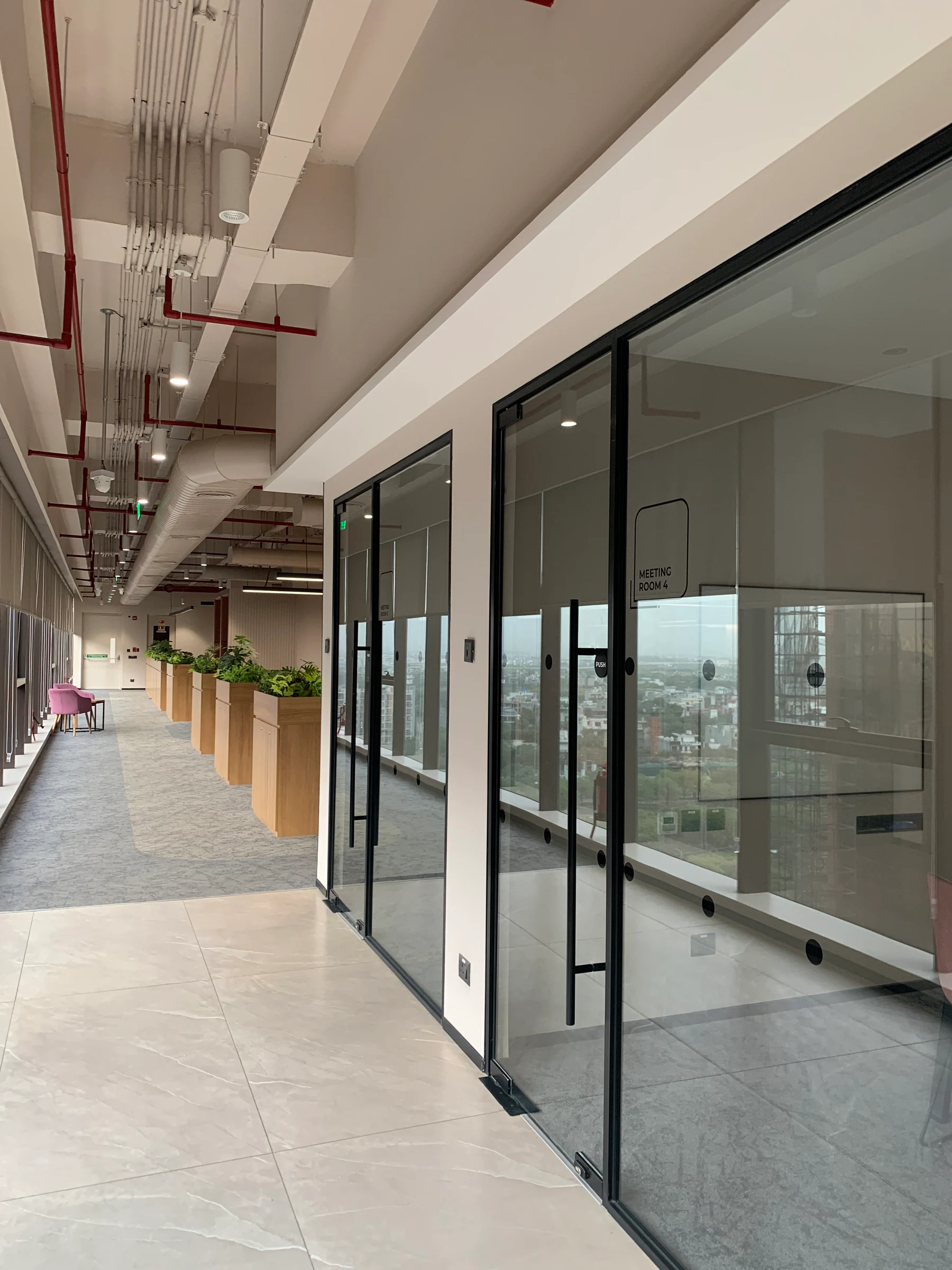 Glass meeting rooms and the collaboration corridor at Vinove's Noida office